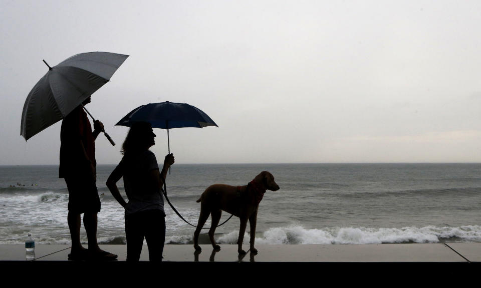 A couple and their dog stand of the seawall prior the landfall of Hurricane Willa, in Mazatlan, Mexico, Tuesday, Oct. 23, 2018. Emergency officials said they evacuated more than 4,250 people in coastal towns and set up 58 shelters ahead of the dangerous Category 3 storm. (AP Photo/Marco Ugarte)