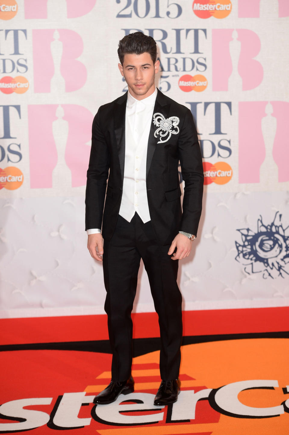 Because plain black is just so boring, Nick Jonas accessorizes his suit with a diamond brooch.