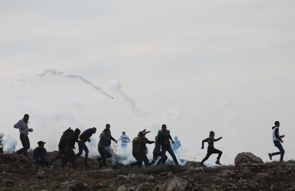 Palestinians run from the tear gas fired by Israeli troops during a protest in Jalazoun refugee camp near the West Bank city of Ramallah, Friday, Feb. 21, 2014. The Palestinians protested against the killing of Mohammad Mubarak by the Israeli military in January. The military then said the incident was sparked when the man opened fire on soldiers, while his family disputed the account, saying he was killed without provocation. (AP Photo/Majdi Mohammed)