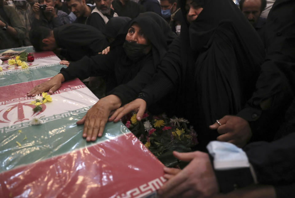 Relatives mourn over the flag draped coffin of Iran's Revolutionary Guard Col. Hassan Sayyad Khodaei who was killed on Sunday, in his funeral ceremony in Tehran, Iran, Tuesday, May 24, 2022. Iran's hard-line President Ebrahim Raisi vowed revenge on Monday over the killing of Sayyad Khodaei who was shot at his car by two assailants outside his home in Tehran, a still-mysterious attack on the country's powerful paramilitary force. (AP Photo/Vahid Salemi)