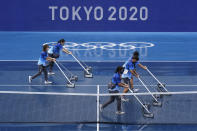 Workers push water off of a court during a rain delay in the tennis competition at the 2020 Summer Olympics, Tuesday, July 27, 2021, in Tokyo, Japan. (AP Photo/Patrick Semansky)