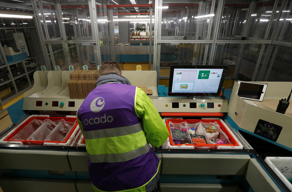 A worker loads a grocery order into baskets at a ocado