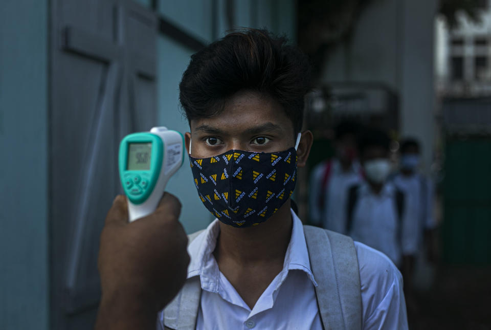 An employee checks the temperature of a student as schools in north-eastern Assam state reopen after being closed for months due to the coronavirus pandemic in Gauhati, India, Monday, Nov. 2, 2020. (AP Photo/Anupam Nath)