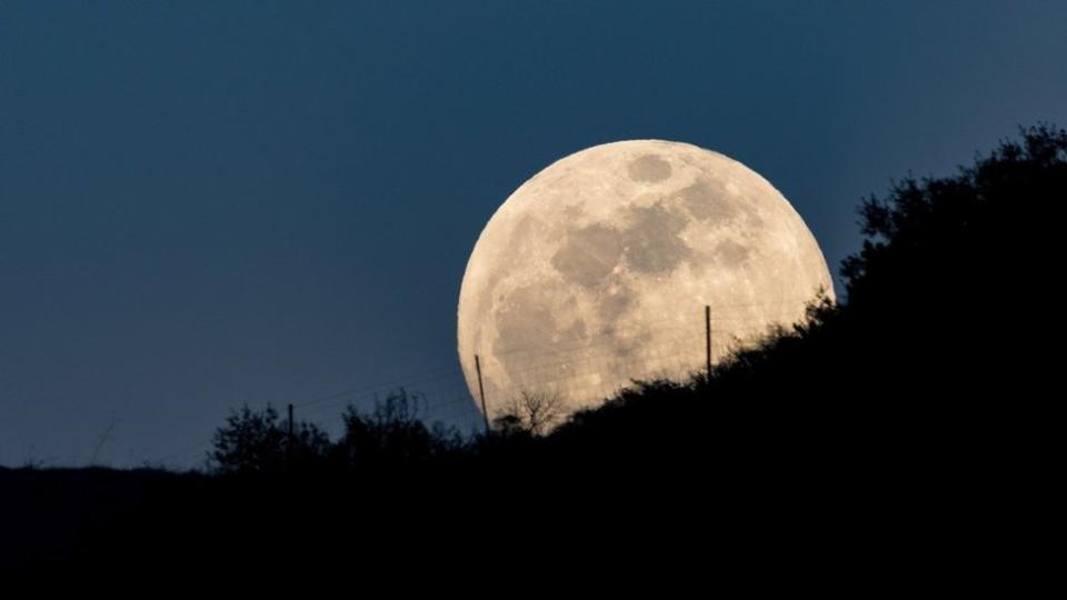 La luna aparece en una colina