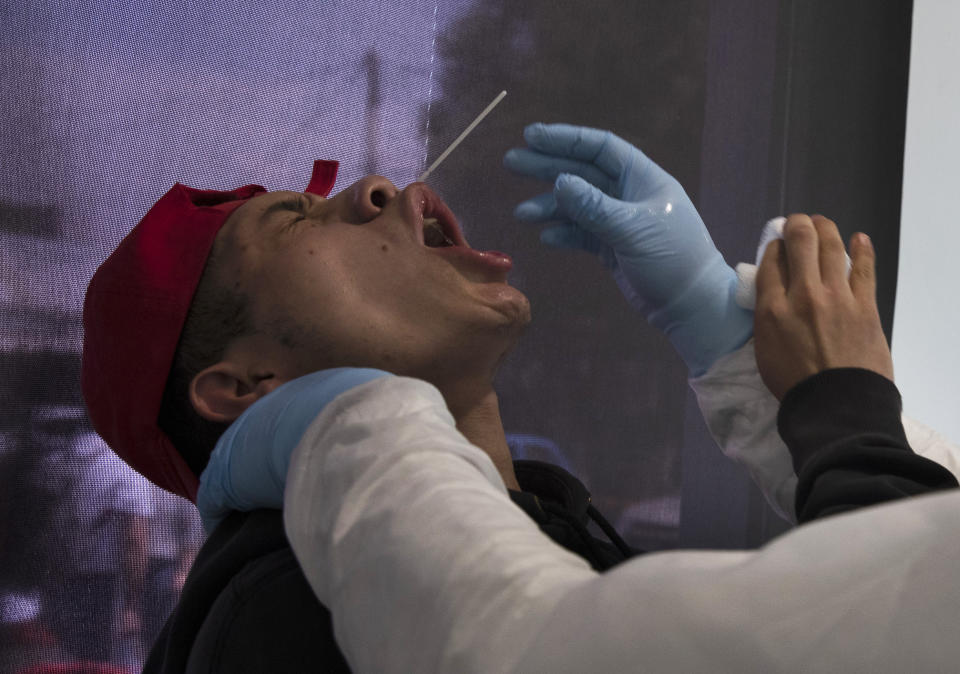 Health worker Ulises Cadena Santana uses a nasal swab to test a man for the new coronavirus, at the Central de Abasto market in Mexico City, Thursday, June 18, 2020. Cadena Santana works taking as many as 100 COVID-19 test samples per day at a series of emergency testing and triage tents set up outside the market. (AP Photo/Marco Ugarte)