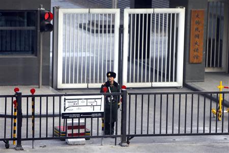 A paramilitary police official stands guard behind a gate at the South Korea embassy in Beijing December 6, 2013. REUTERS/Jason Lee