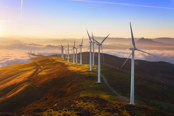 Wind turbines on a large hill above the clouds.