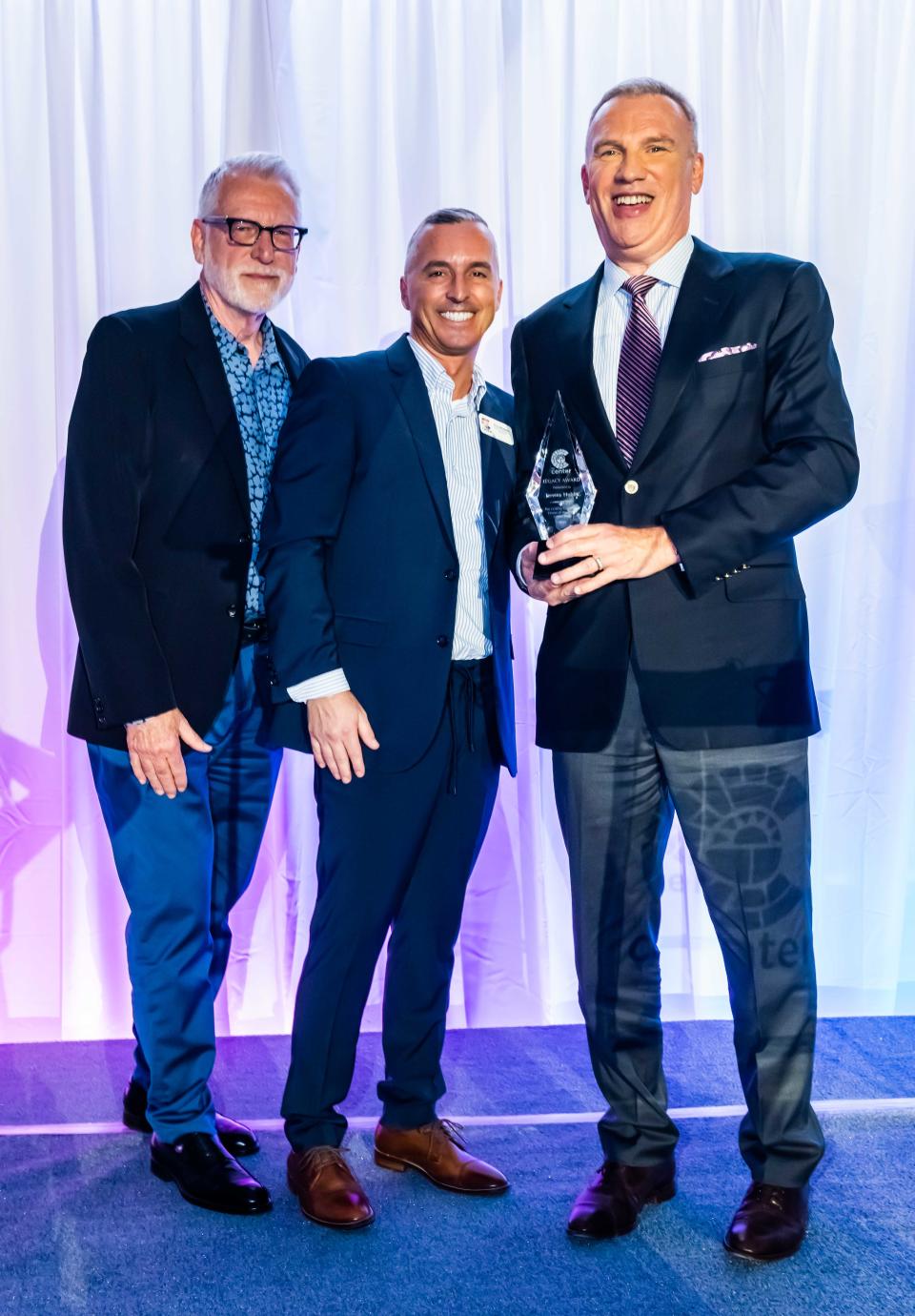 Rob Wheeler (center) congratulates Legacy Award honoree Jeremy Hobbs (right) at Center Stage 2022 on Oct. 21, 2022.