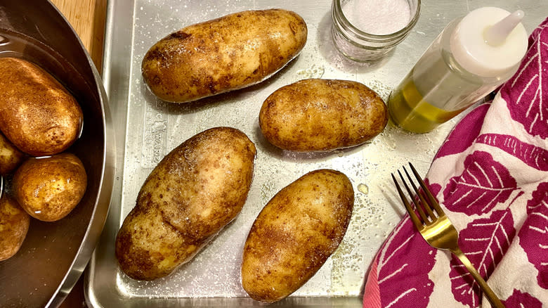 preparing potatoes for baking with oil, salt, and pricking with a fork