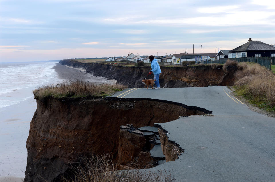 A woman looks over the eroded coastline (Picture: PA)