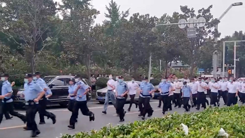 Uniformed and plain-clothed security personnel run to approach demonstrators, outside a People's Bank of China building, who are there protesting over the freezing of deposits by some rural-based banks, in Zhengzhou, Henan province, China July 10, 2022, in this screengrab from video obtained by REUTERS ATTENTION EDITORS - THIS IMAGE HAS BEEN SUPPLIED BY A THIRD PARTY.