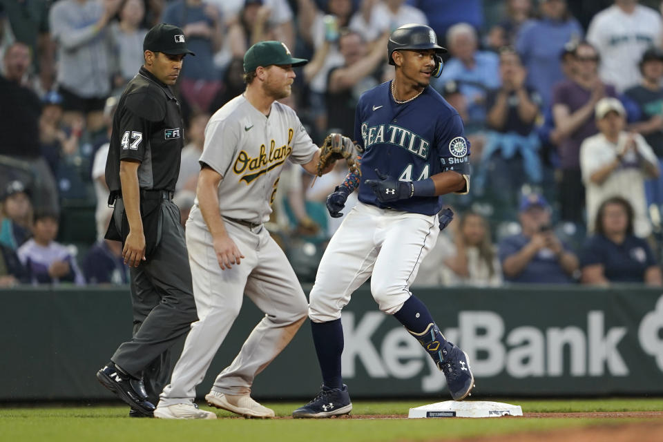 Seattle Mariners' Julio Rodriguez, right, stands next to Oakland Athletics third baseman Sheldon Neuse after hitting a triple during the sixth inning of a baseball game Friday, July 1, 2022, in Seattle. (AP Photo/Ted S. Warren)