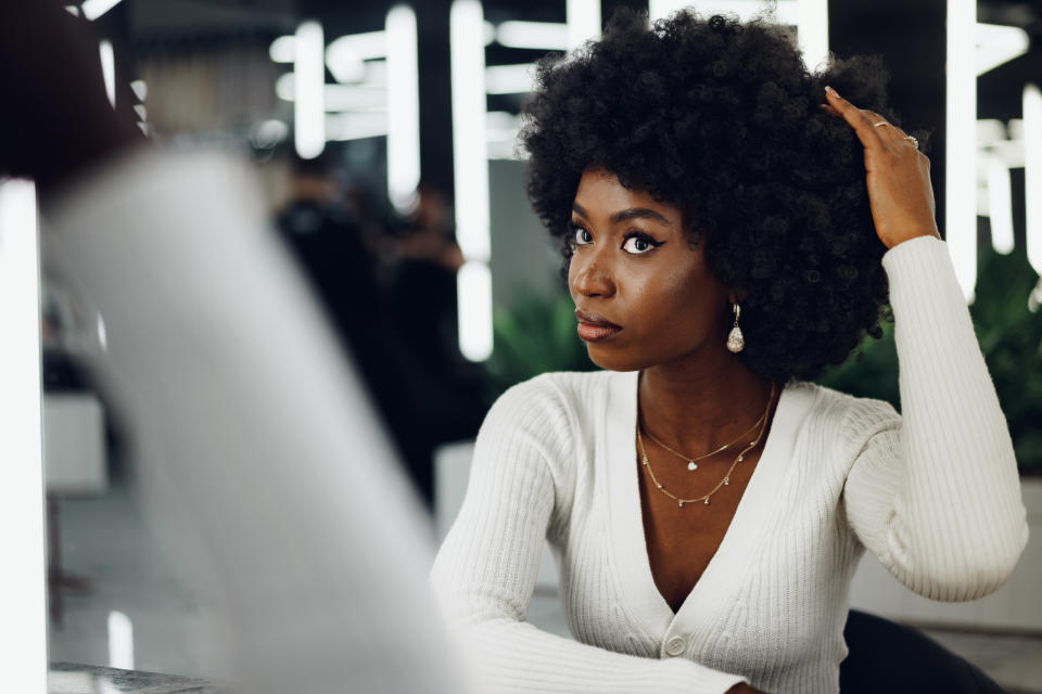 A woman touching her hair and looking in the mirror