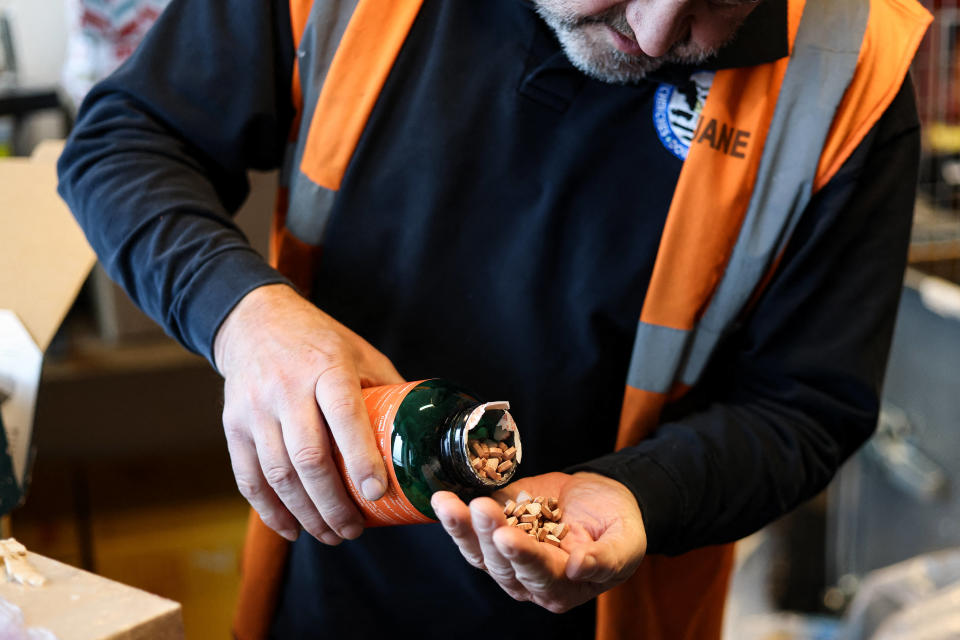 Un douanier belge ouvre un flacon contenant des pilules d’ecstasy alors qu’il contrôle des colis à l’aéroport de Bruxelles