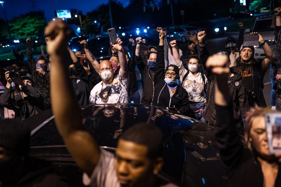 People raise their fists after marching in Flint Township, Michigan, on May 30. Protesters marched to the police department headquarters, where they were met by officers in riot gear before the Genesee County Sheriff agreed to march with them.