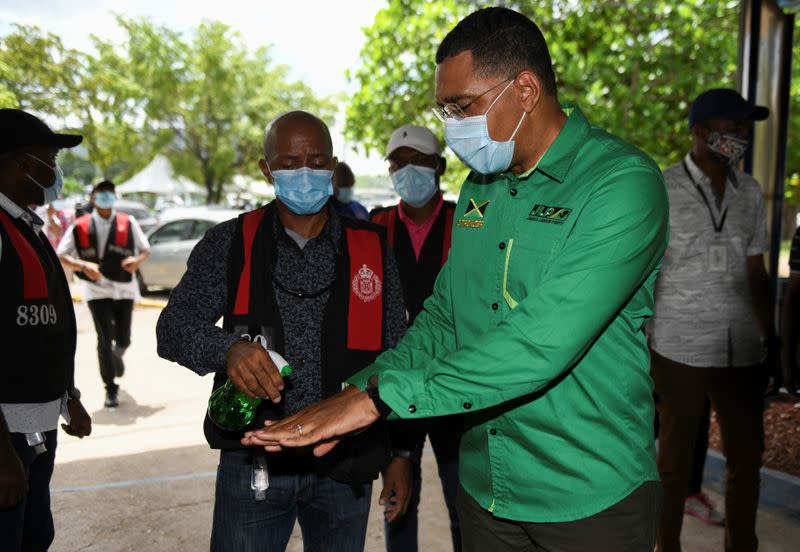 Jamaica's Prime Minister Andrew Holness has his hands sanitized before casting his vote in the general elections, in Kingston