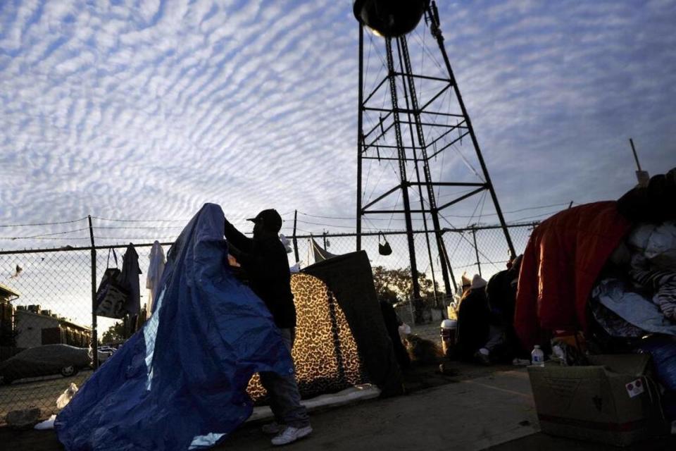 A man sets up a tarp along a sidewalk in Fresno in 2015. The city of Fresno is considering stricter limitations on where the homeless can set up camp, arguing that the measures are necessary for public safety and ADA compliance. ERIC PAUL ZAMORA/Fresno Bee file