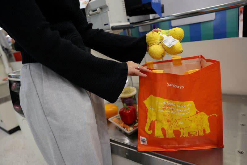 FILE PHOTO: A customer puts groceries inside a reusable bag at the self-checkout inside a Sainsbury’s supermarket in London