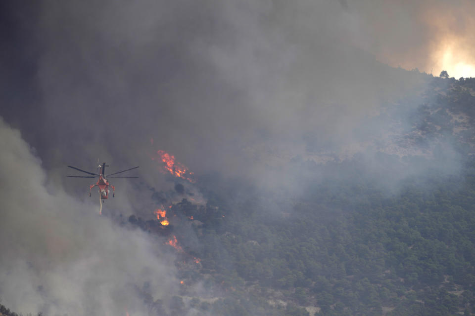 A firefighter helicopter flies toward a wildfire on Parnitha mountain, in Acharnes, northern Athens, Greece, Wednesday, Aug. 23, 2023. Water-dropping planes from several European countries joined hundreds of firefighters Wednesday battling wildfires raging for days across Greece that have left 20 people dead, while major blazes were also burning in Spain's Tenerife and in northwestern Turkey near the Greek border. (AP Photo/Thanassis Stavrakis)