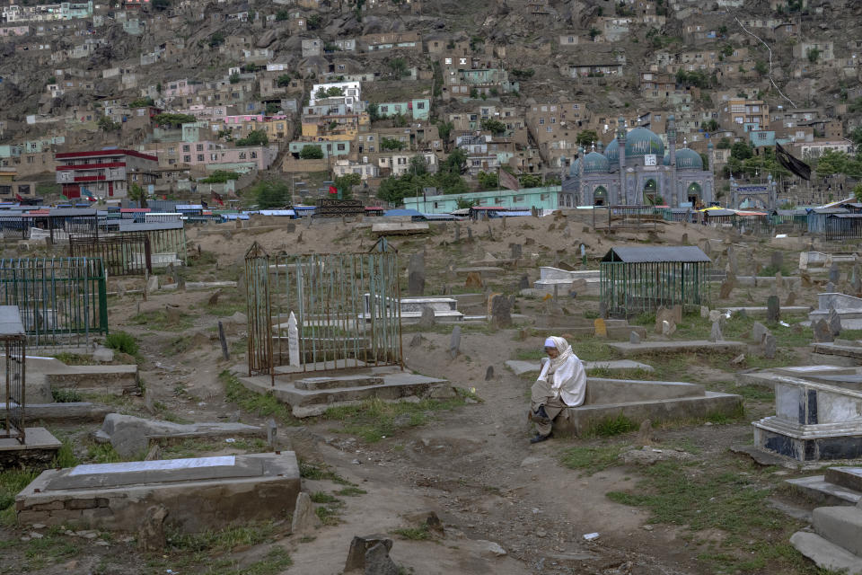 An Afghan man sits on a grave at a cemetery in Kabul, Afghanistan, Wednesday, May 4, 2022. There are cemeteries all over Afghanistan's capital, Kabul, many of them filled with the dead from the country's decades of war. They are incorporated casually into Afghans' lives. They provide open spaces where children play football or cricket or fly kites, where adults hang out, smoking, talking and joking, since there are few public parks. (AP Photo/Ebrahim Noroozi)