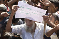 An elderly Rohingya refugee holds a placard during a protest against the repatriation process at Unchiprang refugee camp near Cox's Bazar, in Bangladesh, Thursday, Nov. 15, 2018. The head of Bangladesh's refugee commission said plans to begin a voluntary repatriation of Rohingya Muslim refugees to their native Myanmar on Thursday were scrapped after officials were unable to find anyone who wanted to return. (AP Photo/Dar Yasin)