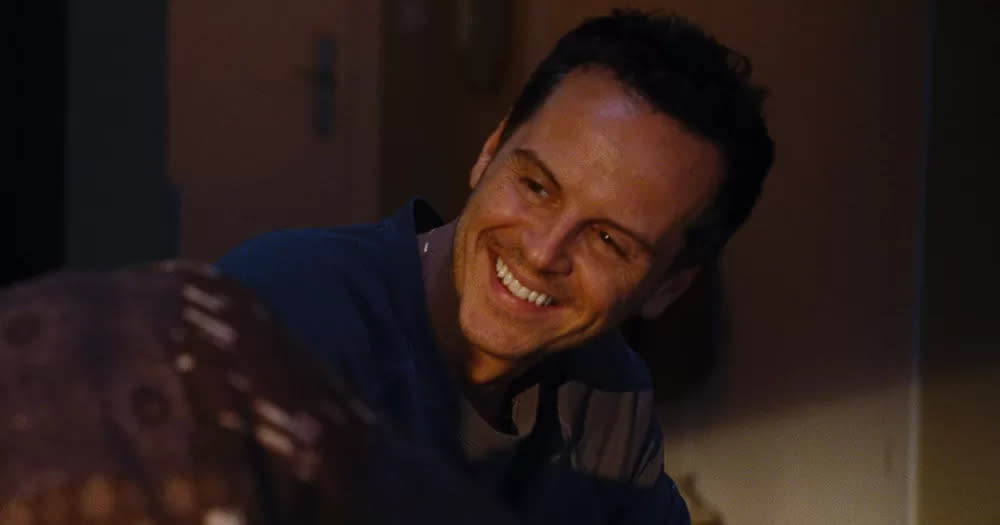 Still of gay actor Andrew Scott from All of Us Strangers. He is leaning over and smiling, looking at someone out of frame.