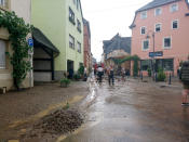 <p>Anwohner der Gemeinde Lieser beseitigen nach dem Unwetter Schlamm und Unrat auf den Straßen der Innenstadt. Über Mosel und Hunsrück kam es zu heftigen Wolkenbrüchen. Teilweise wurden Keller überflutet, auf Weinbergen lösten sich Geröll und Schlamm. (Bild: Steil-TV/dpa) </p>