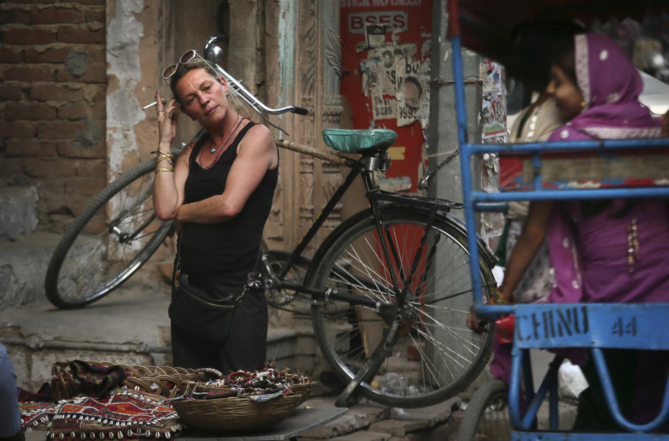 In this Tuesday, April 2, 2013 photo, a foreign tourist smokes a cigarette at a market area in New Delhi, India. Violence against women, and the huge publicity generated by recent attacks here, is threatening India's $17.7 billion tourism industry. A new study shows tourism has plunged, especially among women, since a 23-year-old Indian student was raped on a New Delhi bus and later died from her injuries, a case that garnered worldwide publicity. (AP Photo /Manish Swarup)