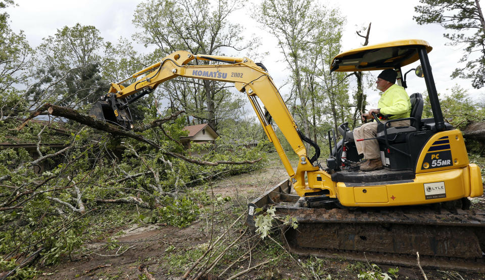 Terrill Harvey, right, uses his heavy machinery to remove debris from a friend's home, Friday, April 19, 2019, in Morton, Miss., as residents begin their cleanup from Thursday's possible tornado touchdown that heavily damaged many homes. Strong storms again roared across the South on Thursday, topping trees and leaving a variety of damage in Mississippi, Louisiana and Texas. (AP Photo/Rogelio V. Solis)