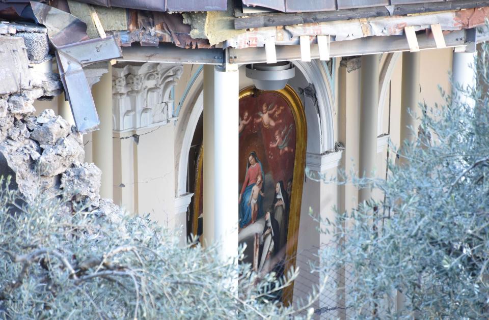 Debris stand near the damaged structure of a Church in Fleri, Sicily Italy, Wednesday, Dec. 26, 2018. A quake triggered by Italy's Mount Etna volcano has jolted eastern Sicily, slightly injuring 10 people and prompting frightened Italian villagers to flee their homes. (Orietta Scardino/ANSA Via AP)