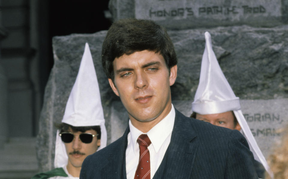 The Imperial Wizard of the National Knights of the Ku Klux Klan, Don Black, in 1982, wearing a suit and tie, with white-gowned Klan members in the background. (Photo: Bettmann Archive via Getty Images)