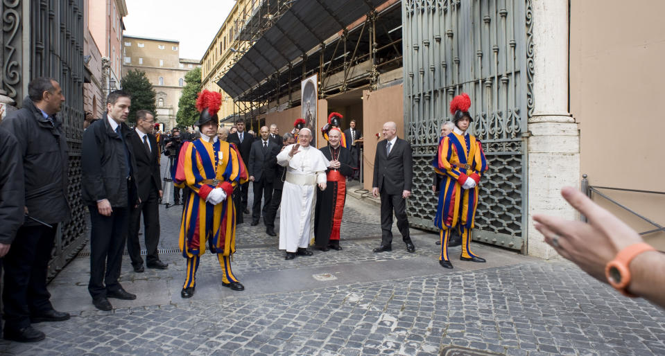 Pope Francis greets faithful at the Vatican, Sunday, March 17, 2013. Pope Francis began his first Sunday as pontiff by making an impromptu appearance to the public from a side gate of the Vatican, startling passersby and prompting cheers, then kept up his simple, spontaneous style by delivering a brief, off-the-cuff homily at the Vatican's tiny parish church. Dressed only in white cassock, Francis waved to the crowd in the street outside St. Anna's Gate and before entering the church, which serves Vatican City State's hundreds of residents, he shook hands of the parishioners and kissed babies. (AP Photo/Antonello Nusca)