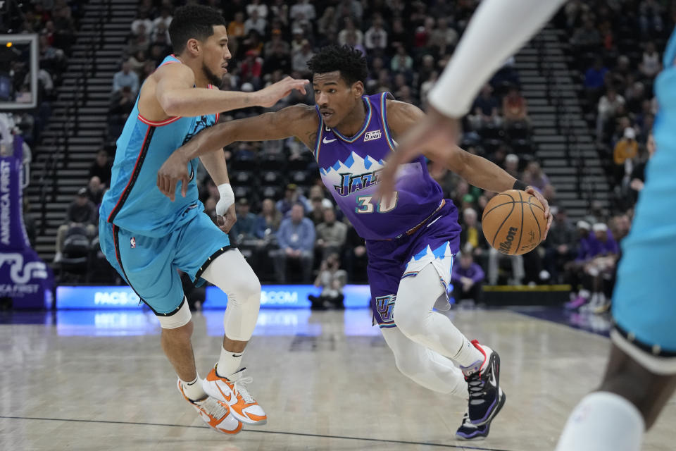 Utah Jazz guard Ochai Agbaji (30) drives as Phoenix Suns guard Devin Booker, left, defends during the first half of an NBA basketball game Monday, March 27, 2023, in Salt Lake City. (AP Photo/Rick Bowmer)