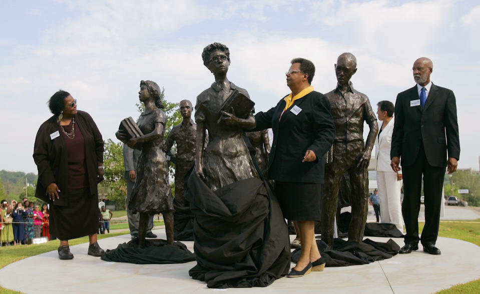 FILE - In this Aug. 30, 2005 file photo, Elizabeth Eckford, center, removes a veil from a statue of herself as Melba Pattillo Beals, left, Dr. Terrence Roberts, right, and other members of the Little Rock Nine participate on the grounds of the Arkansas state Capitol in Little Rock. A proposal on Thursday, Jan. 16, 2020, to erect a memorial to Ohio women who fought for voting rights would add the Statehouse to a small group of state capitols with monuments to actual female figures from U.S. history. (AP Photo/Danny Johnston, File)