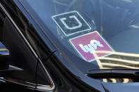 FILE - A ride share car displays Lyft and Uber stickers on its front windshield in downtown Los Angeles, Jan. 12, 2016. Ride-hailing companies Uber and Lyft said Monday, May 20, 2024, they will keep operating in Minnesota now that state lawmakers have passed a measure that will increase driver pay, but at a lower rate than approved by Minneapolis officials earlier this year. (AP Photo/Richard Vogel, File)