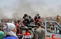 <p>Palestinian men bring tires to be burned during clashes with Israeli forces near the border between the Gaza Strip and Israel, east of Gaza City, on May 14, 2018, as Palestinians protest the inauguration of the U.S. Embassy following its controversial move to Jerusalem. (Photo: Mahmud Hams/AFP/Getty Images) </p>