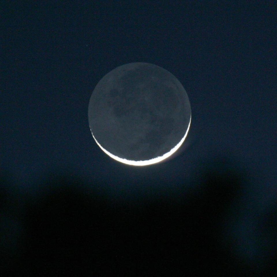 A thin waxing crescent Moon is seen just after Sunset, in Tyler, Texas on Friday, Feb. 8, 2008, one day after the Moon passed in front of the Sun causing an annular Solar eclipse. The nightside of the Moon is lit by reflected light from the dayside of the Earth and is known as Earthshine.