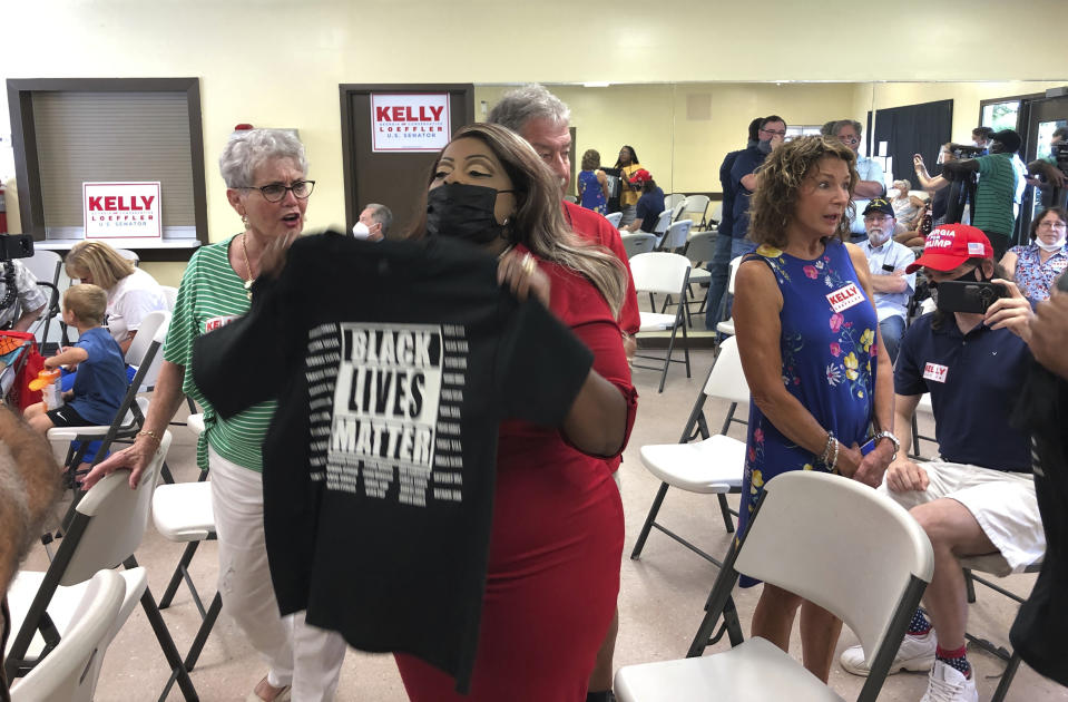 CORRECTS LAST NAME TO JAMES, NOT GAINES - Triana Arnold James holds up a Black Lives Matter T-shirt as she protests a speech by U.S. Sen Kelly Loeffler, Thursday, Sept 3, 2020, in Cumming, Ga. James and a fellow activist kept Loeffler from finishing a campaign speech. (AP Photo/Jeff Amy)