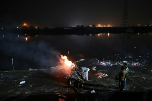 A man lights up a funeral pyre for a friend who died in this week's Delhi riots