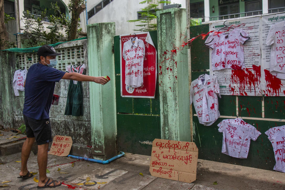 An anti-coup protester splashes red paint on student uniforms after they hanged them outside a school during a demonstration against the re-opening of the school by the junta government at Yangon, Myanmar, Tuesday, April 27, 2021. Demonstrations have continued in many parts of the country since Saturday's meeting of leaders from the Association of Southeast Asian Nations, as have arrests and beatings by security forces despite an apparent agreement by junta leader Senior Gen. Min Aung Hlaing to end the violence. (AP Photo)