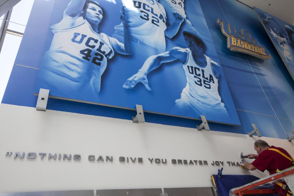 In this photo taken Tuesday, Oct. 23, 2012, a worker sets a quote from legendary Bruins basketball coach John Wooden on a concourse wall at the renovated Pauley Pavilion on the UCLA campus in Los Angeles. The UCLA Bruins honor their championship past and address the future in the $132 million renovation to be unveiled on Nov. 9 when they host Indiana State in their men’s basketball season opener. (AP Photo/Damian Dovarganes)