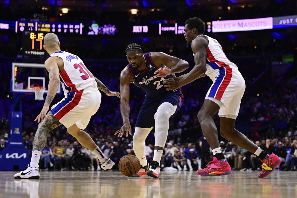 Philadelphia 76ers' Joel Embiid, center, dribbles the ball between the defense of Detroit Pistons' Evan Fournier (31) and Jalen Duren (0) during the first half of an NBA basketball game, Tuesday, April 9, 2024, in Philadelphia. (AP Photo/Derik Hamilton)