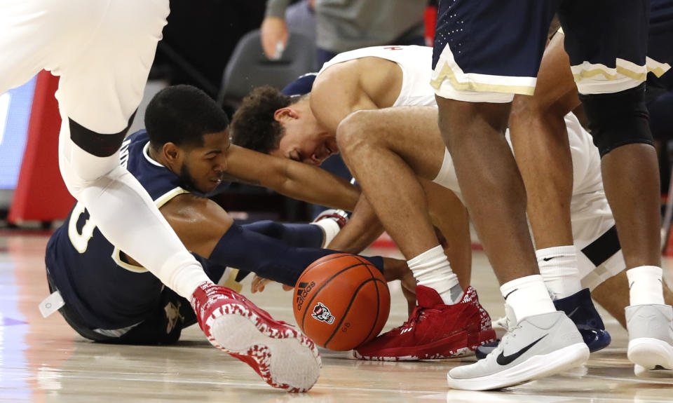 North Carolina State's Jericole Hellems (4) and Charleston Southern's Travis Anderson, left, go after a loose ball during an NCAA college basketball game in Raleigh, N.C., Wednesday, Nov. 25, 2020. (Ethan Hyman/The News & Observer via AP)