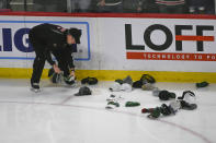 A worker picks up hats that were tossed on the ice after Minnesota Wild's Matt Boldy scored his third goal for a hat trick during the third period of an NHL hockey game against the Seattle Kraken, Monday, March 27, 2023, in St. Paul, Minn. (AP Photo/Craig Lassig)