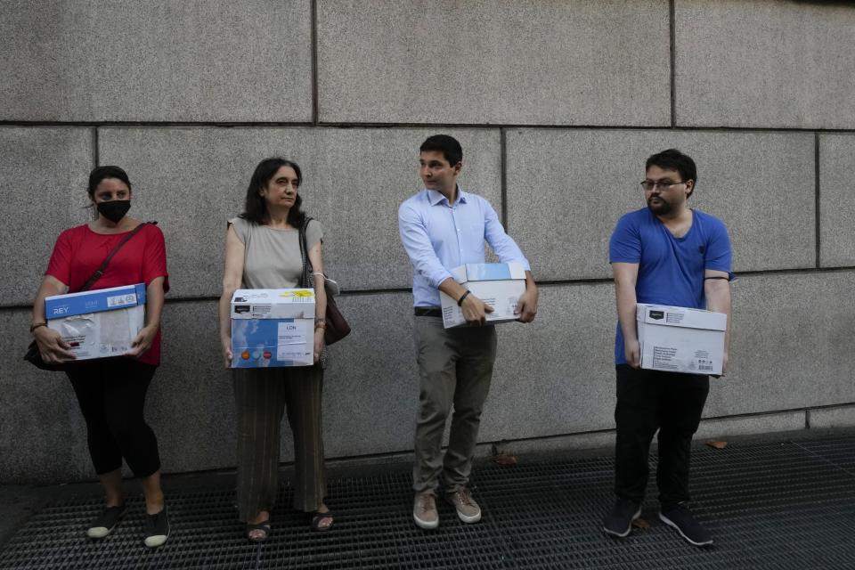 Members of an Italian association for consumer protection, hold boxes containing documents as they wait outside the Genoa's Palace of Justice during the opening of the first hearing of the trial for the Morandi bridge collapse, Thursday, July 7, 2022. Forty-three people were killed when a large stretch of the Morandi Bridge broke off August 14, 2018, on the eve of one of Italy's biggest vacation holidays. (AP Photo/Antonio Calanni)