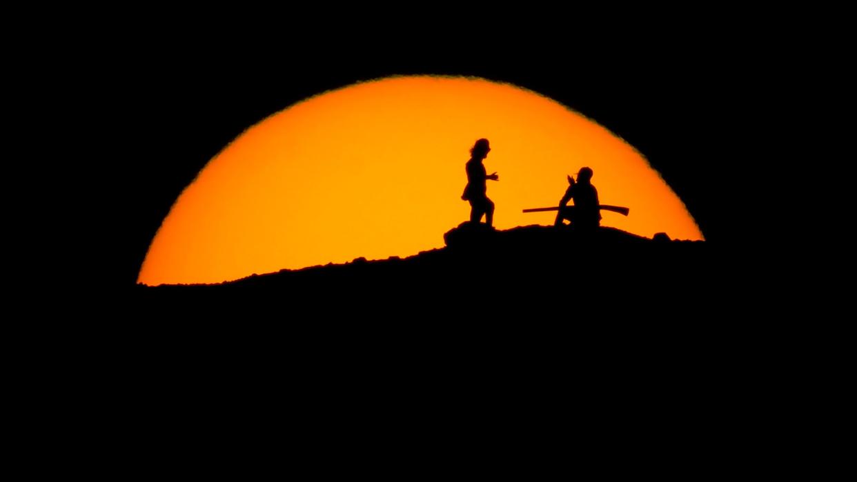 Hikers watch the sunset Saturday from a peak at Papago Park in Phoenix. (Photo: Charlie Riedel/Associated Press)