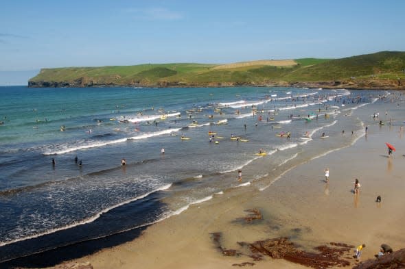 Surfers and swimmers on the beach at Polzeath, Cornwall.