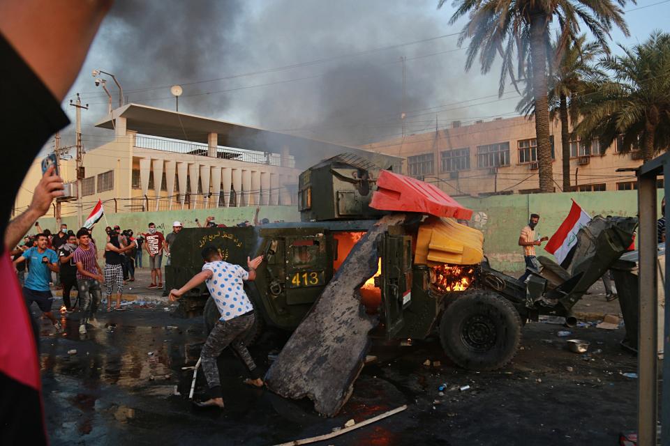 Anti-government protesters burn an armored vehicle belonging to the Federal Police Rapid Response Forces during a protest in Baghdad, Iraq, Thursday, Oct. 3, 2019. Iraqi security forces fired live bullets into the air and used tear gas against a few hundred protesters in central Baghdad on Thursday, hours after a curfew was announced in the Iraqi capital on the heels of two days of deadly violence that gripped the country amid anti-government protests that killed over 19 people in two days. (AP Photo/Hadi Mizban)