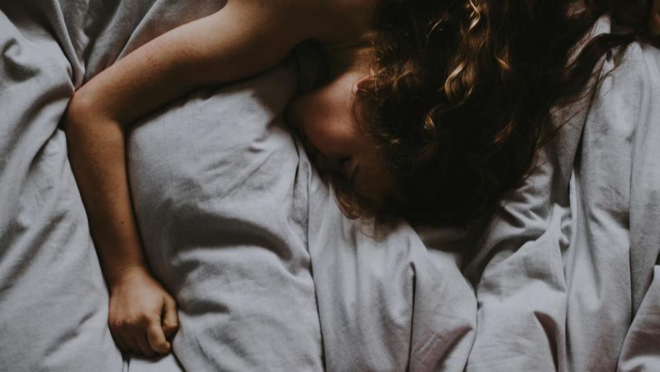 A woman sleeping in a bed with her arm outstretched