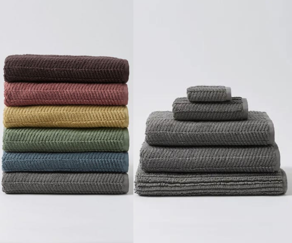 On the left six towels in grey, blue, green, mustard, dusty pink and brown are stacked on top of each other on a light grey background, while on the right, three grey towels are stacked ontop of each other with two smaller ones ontop.